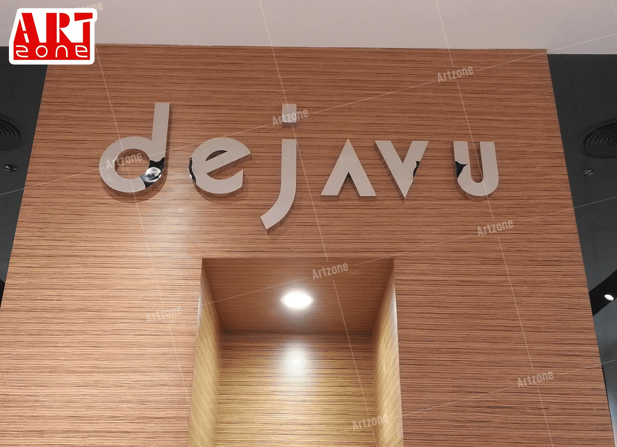 لافتة "dejavu" ثلاثية الأبعاد فضية على جدار خشبي، بجوار منطقة "ART ZONE".