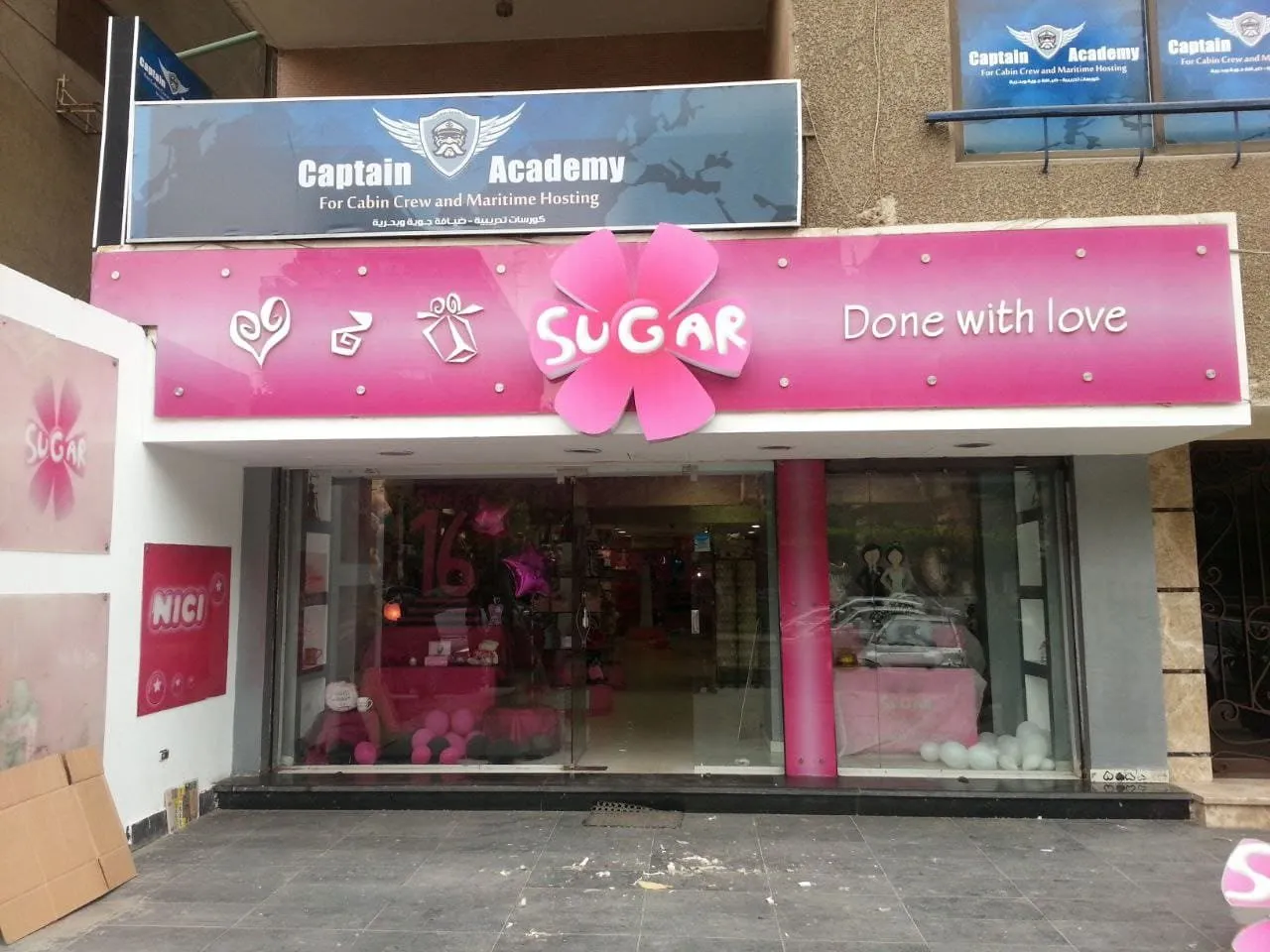 واجهة متجر "SUGAR" الوردي الزاهي للهدايا والديكورات، مع لافتة "Done with love".