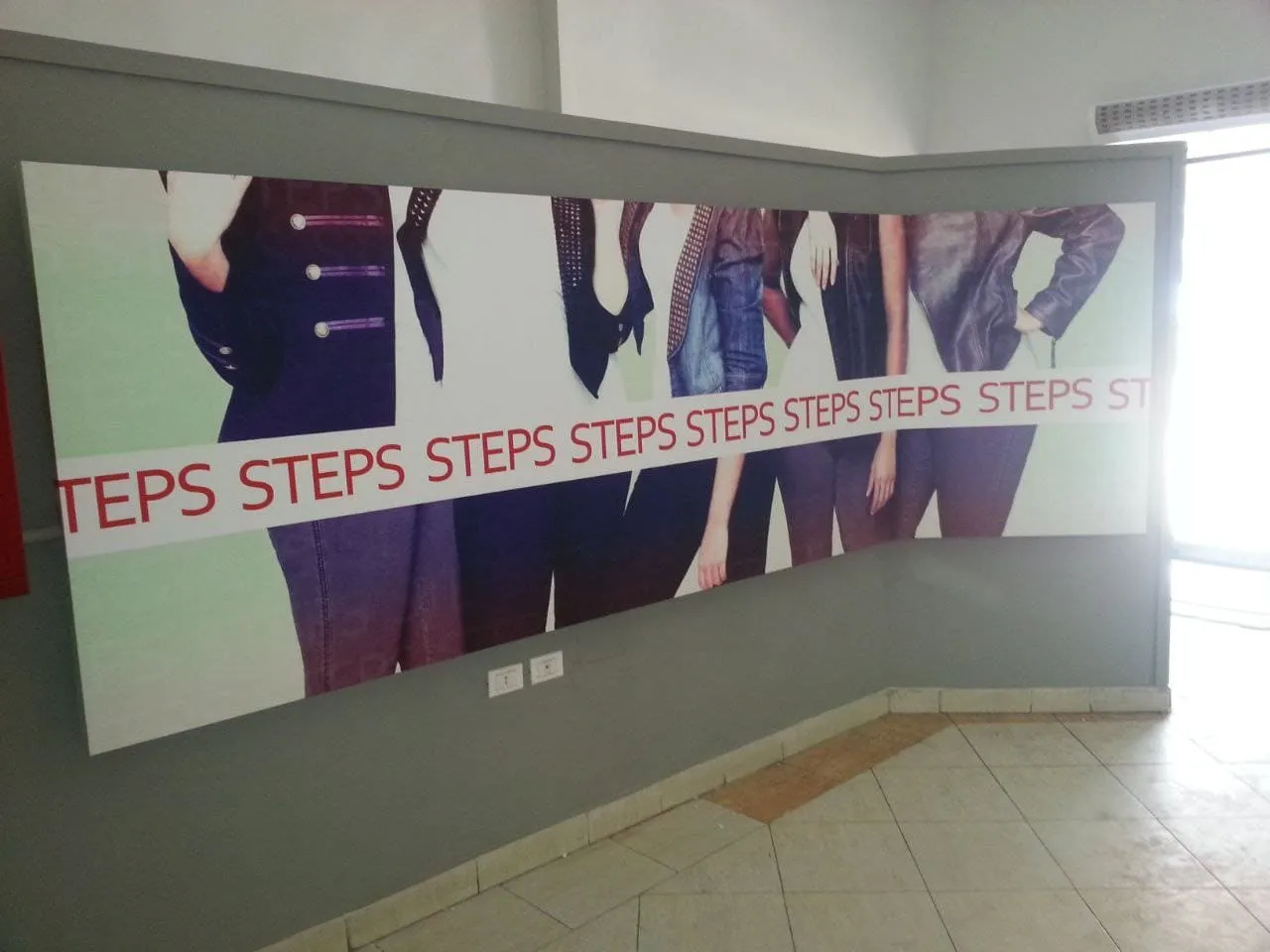 ملصق أزياء عصري لكلمة "STEPS" يركز على ملابس وإكسسوارات داكنة مع إضاءة قوية.