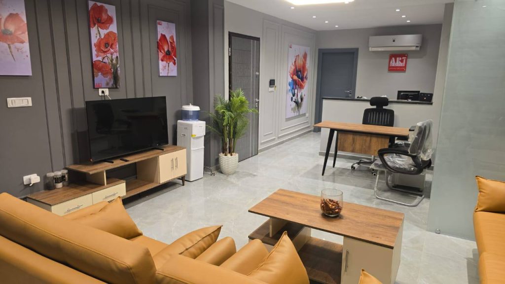 تصميم داخلي حديث لشركة إعلانات: أريكة جلدية، لوحات فنية، وديكور خشبي.