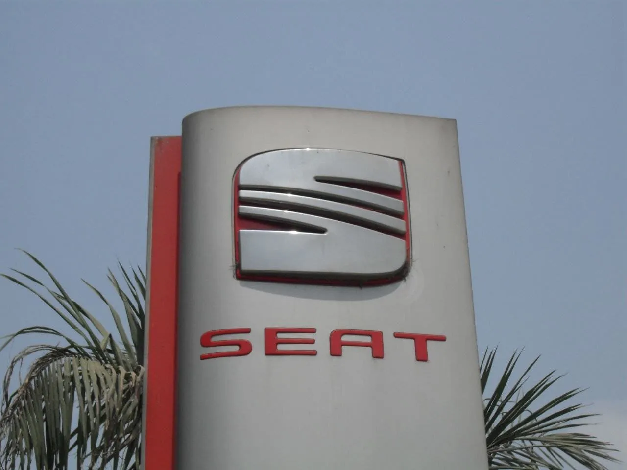 لافتة عمودية كبيرة تحمل شعار SEAT الأحمر في موقع خارجي مشمس.