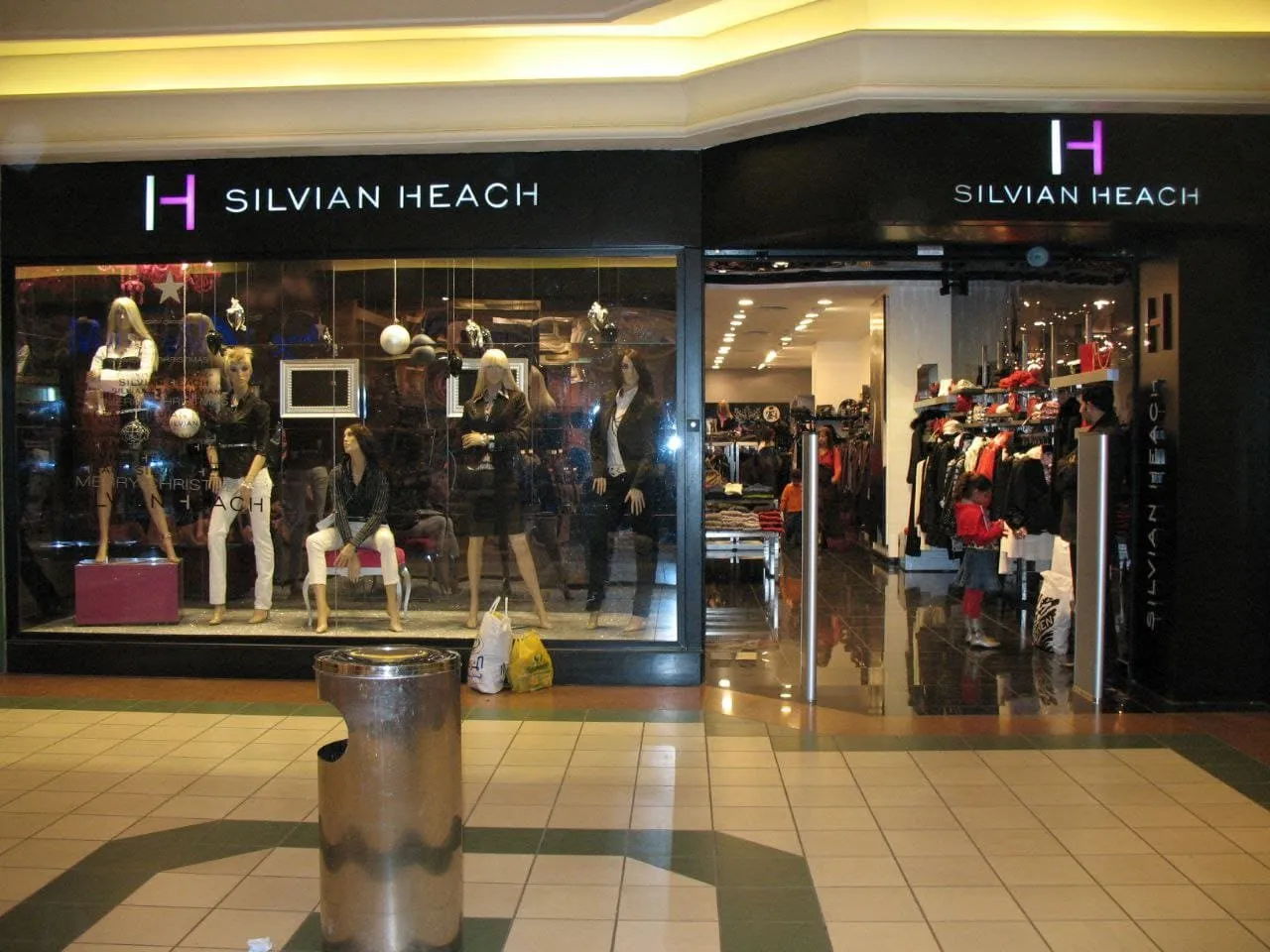 واجهة متجر أزياء نسائية "SILVIAN HEACH" مركز تجاري تعرض ملابس داكنة وعارضات أزياء.