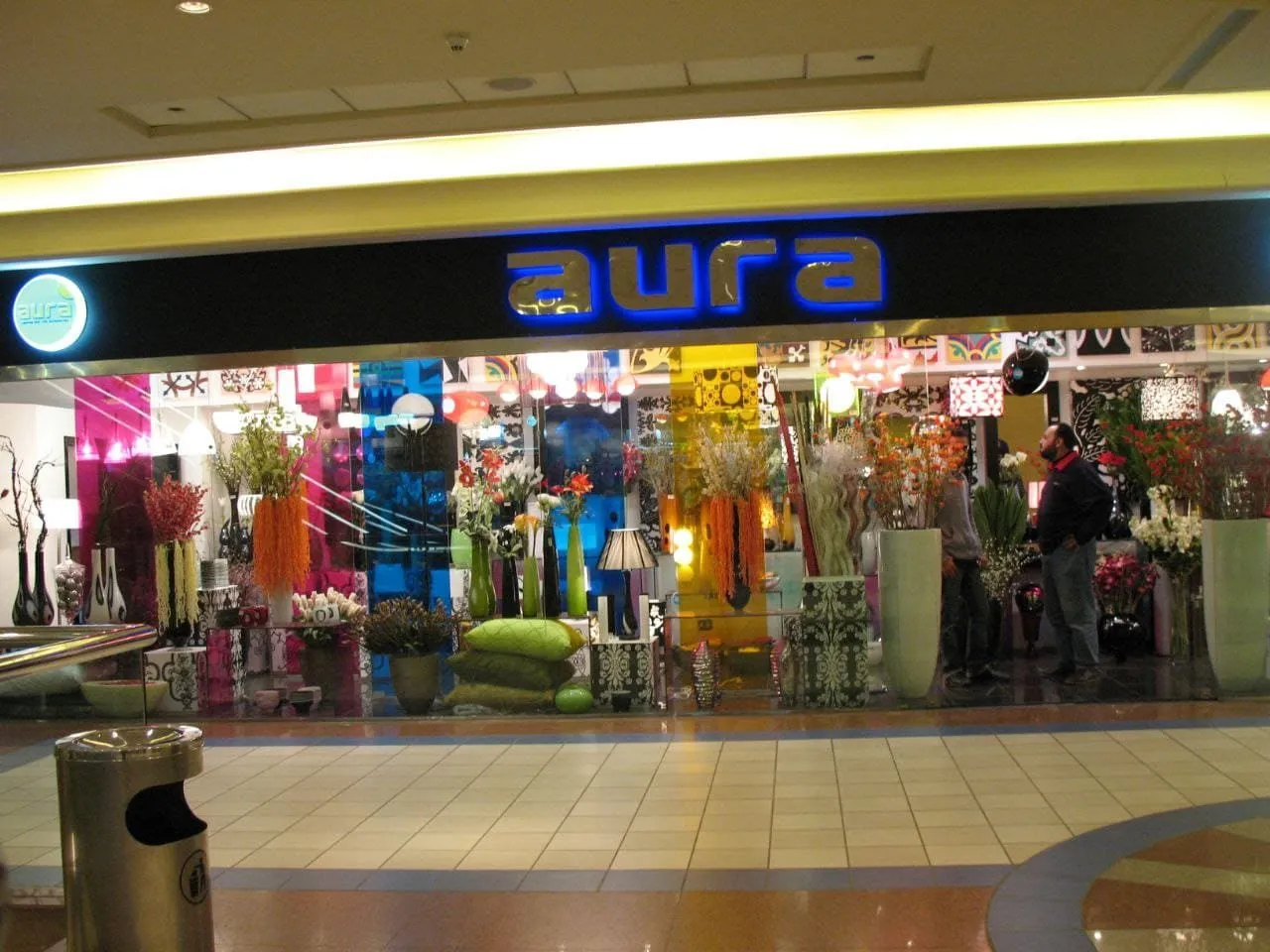 واجهة متجر "aura" لديكورات المنزل الملونة والمزينة بالمزهريات والإضاءة النيون.