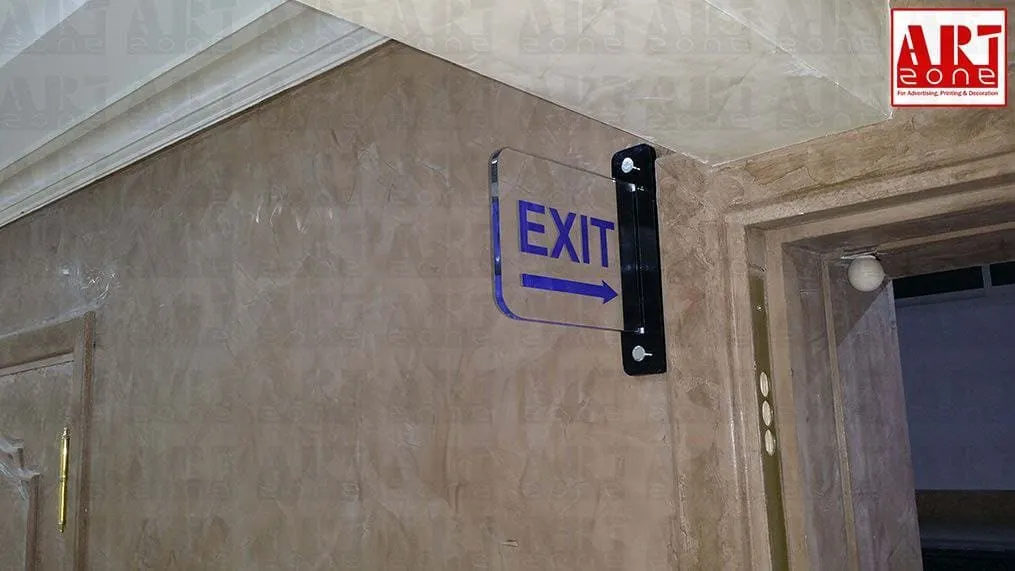 لافتة خروج زرقاء شفافة (EXIT) على جدار رخامي بيج مع حامل أسود.