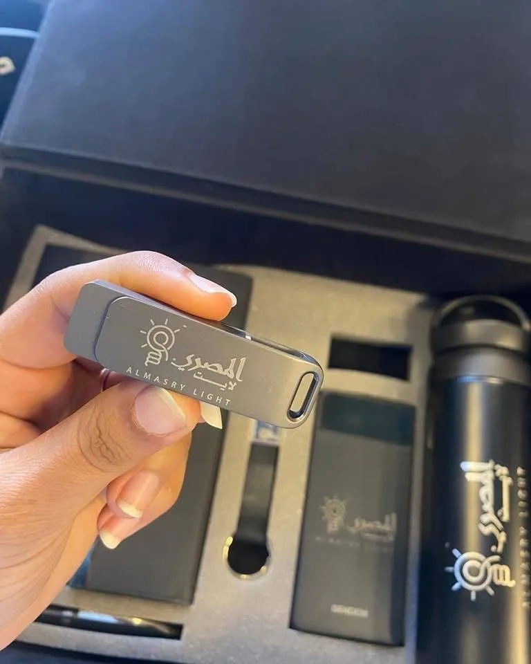 يد تمسك بذاكرة فلاش "المصري ALMASRY LIGHT" ضمن مجموعة هدايا ترويجية سوداء.