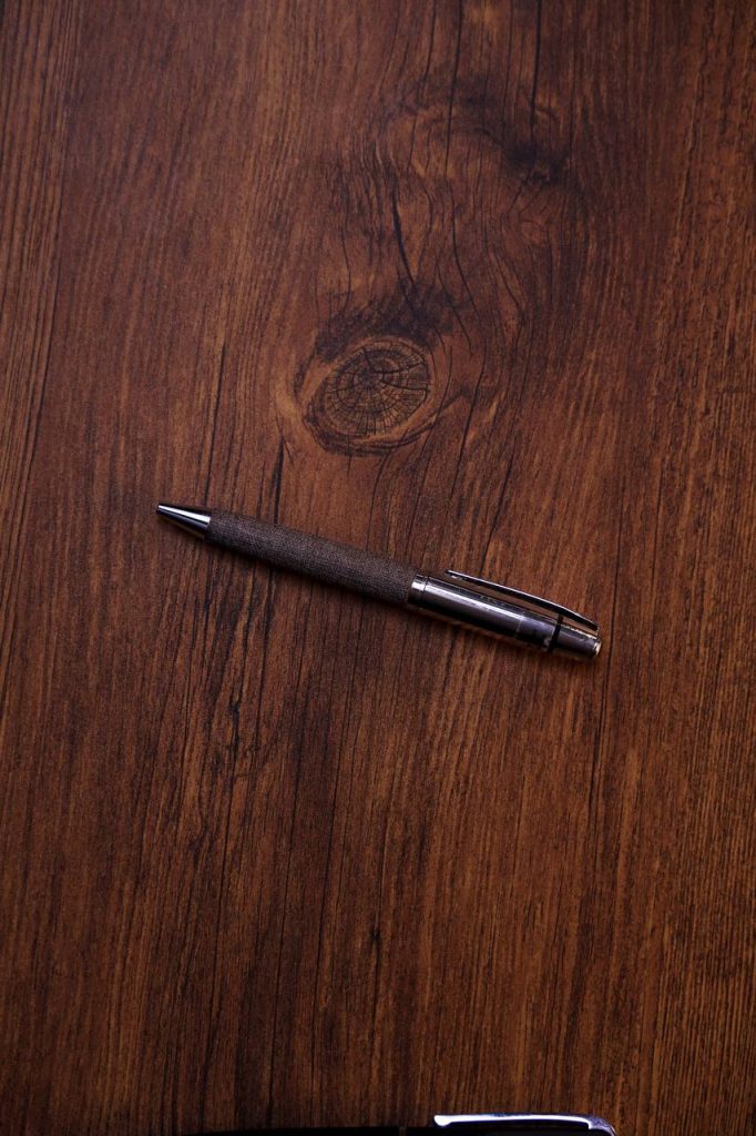 قلم معدني فاخر بتصميم أنيق على سطح خشبي داكن للمنتجات الدعائية.