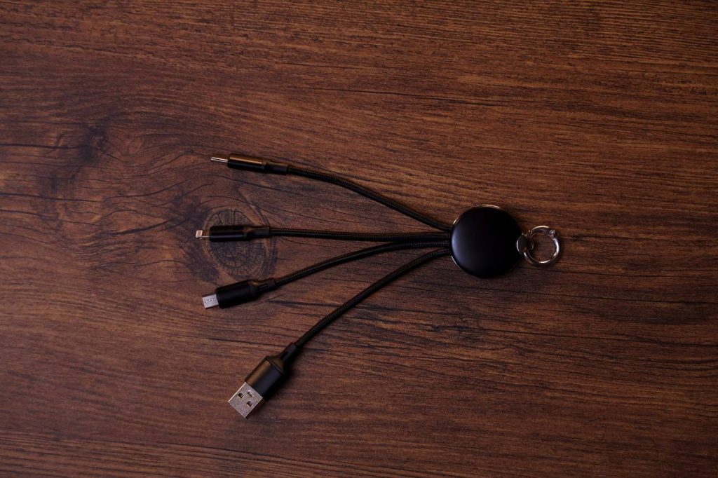 كابل شحن بيانات 3 في 1 أسود مضفر مع حلقة مفاتيح على سطح خشبي.