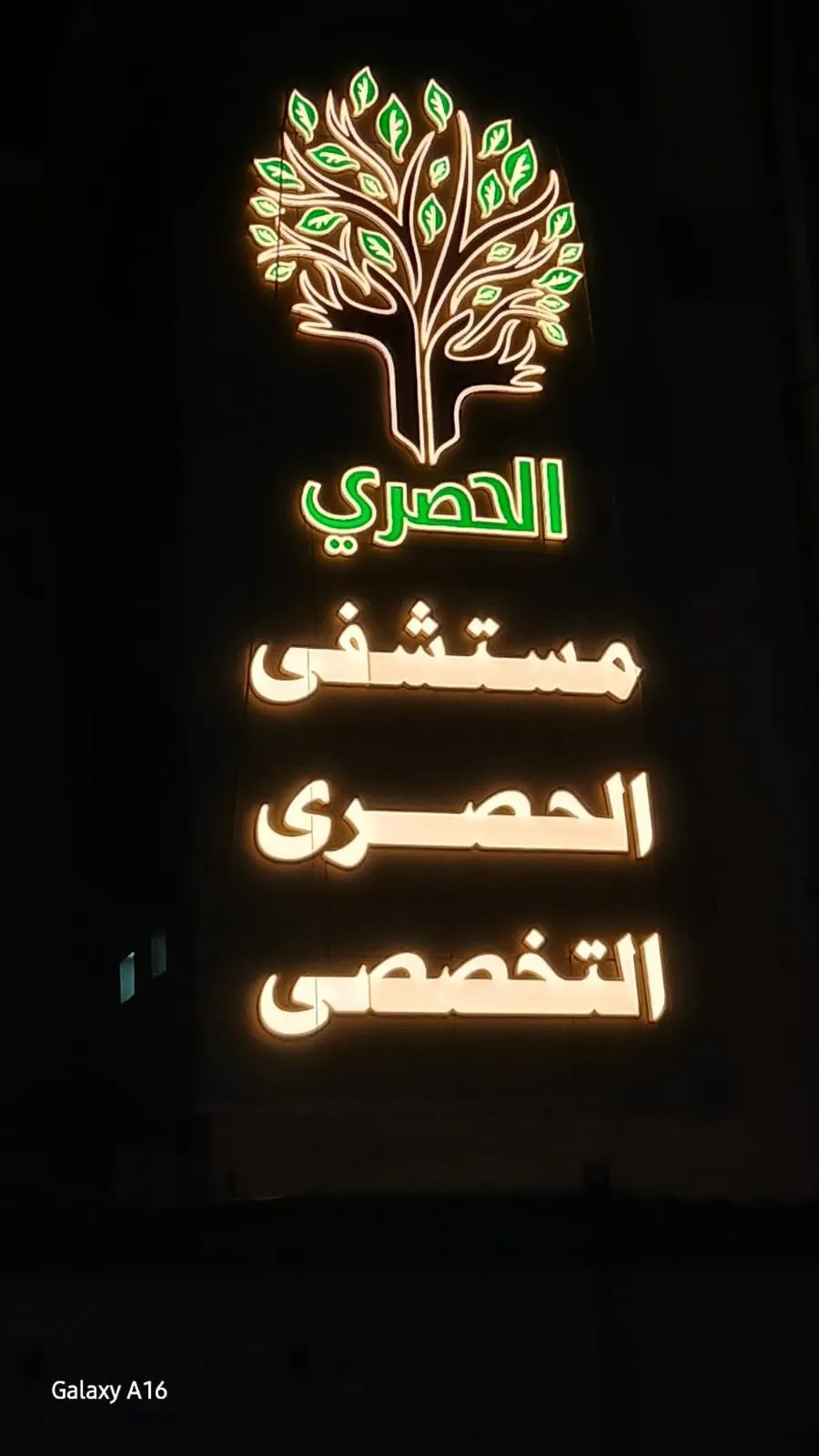 لافتة مركز طبي مضيئة ليلاً بشعار شجرة خضراء ونصوص عربية جذابة.